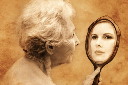 Elderly-woman-holding-hand-mirror-reflecting-young-woman
